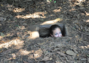 b_tunnel After much contemplation of how to spend our last day in Ho Chi Minh City we chose to make the journey to the Cho Chi Tunnels just outside the city. Eric and I were traveling with 3 of our friends from back home in Atlanta. The journey to the tunnels was fairly quick once we got out of the hustle and bustle of the city. The tunnels offered way more than any of us expected. Upon arrival we were assigned a group and a tour guide. Our tour guide led us through the forest and pointed out the secret passage ways that the Vietnamese used during the war. The first one he uncovered had been widened for us, the fat American's to fit into. Each of us eagerly lowered ourselves into the small chamber and took a quick photo.